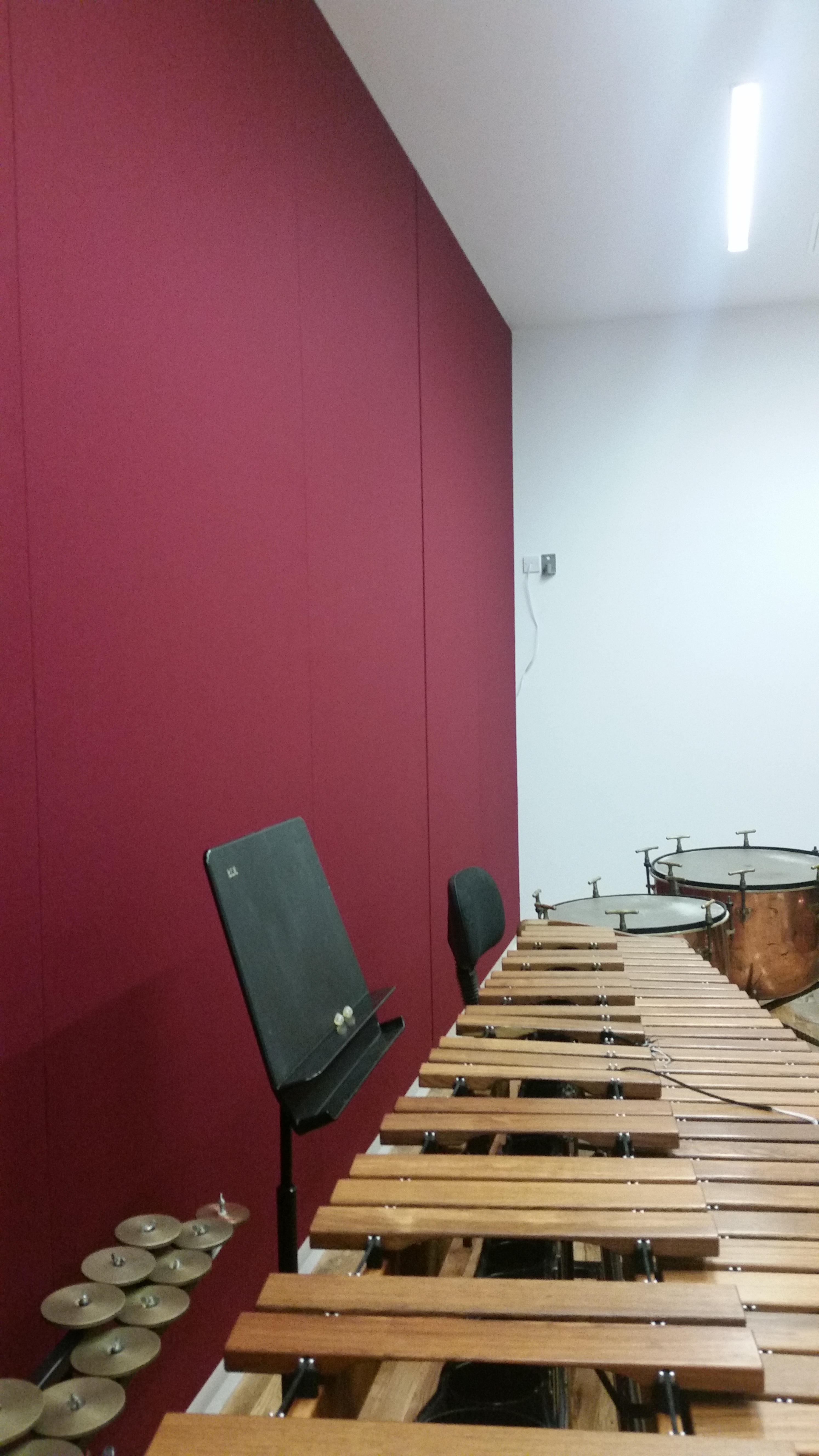 Marimba and timpani drums in a rehearsal space with a maroon wall