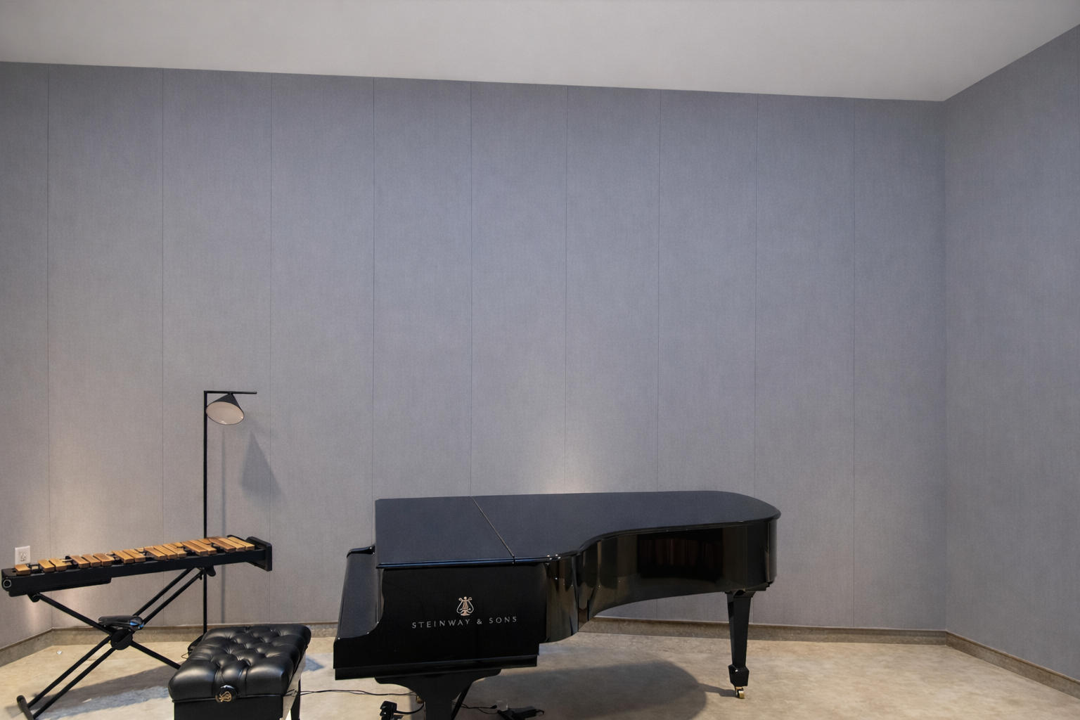 Fabric acoustic wall panels installed behind a piano in a studio interior