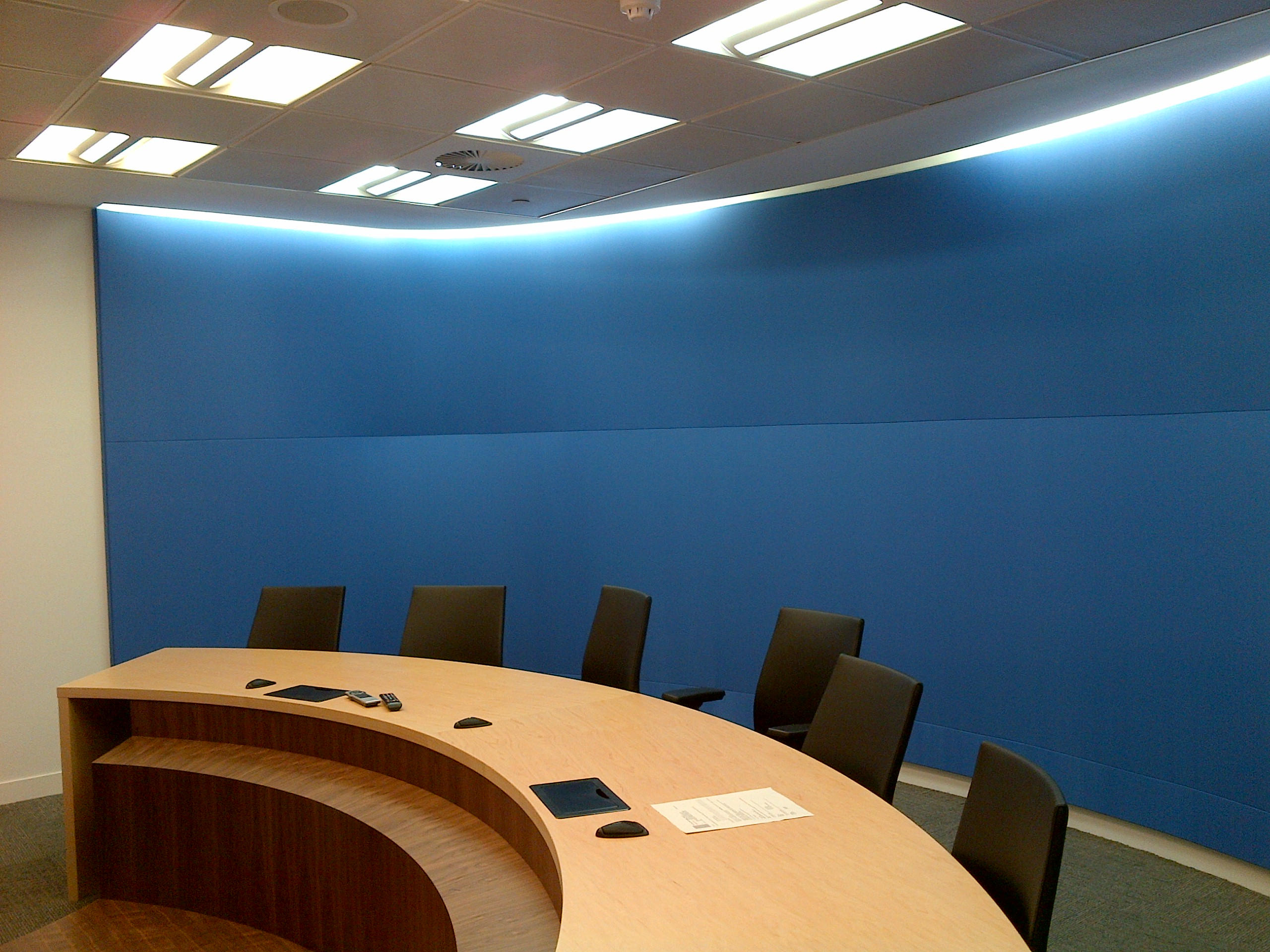 Modern conference room with a curved wooden table and dark chairs