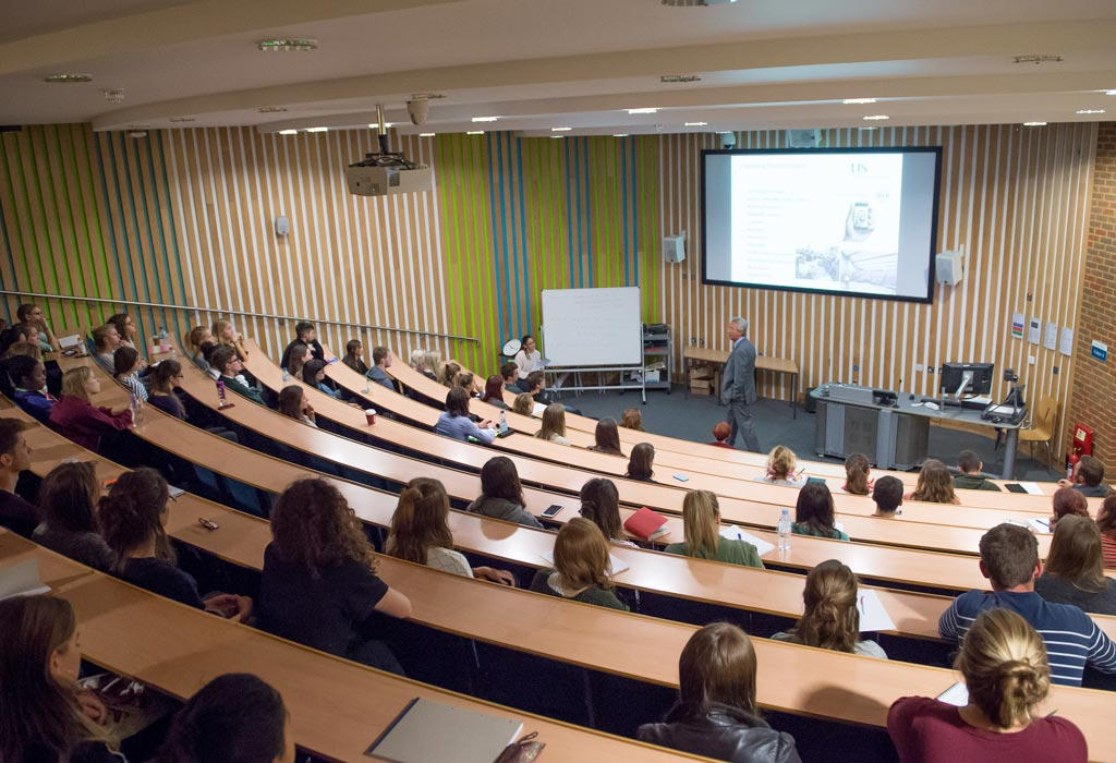 Lecture theatre auditorium with tiered red seating and a projection screen