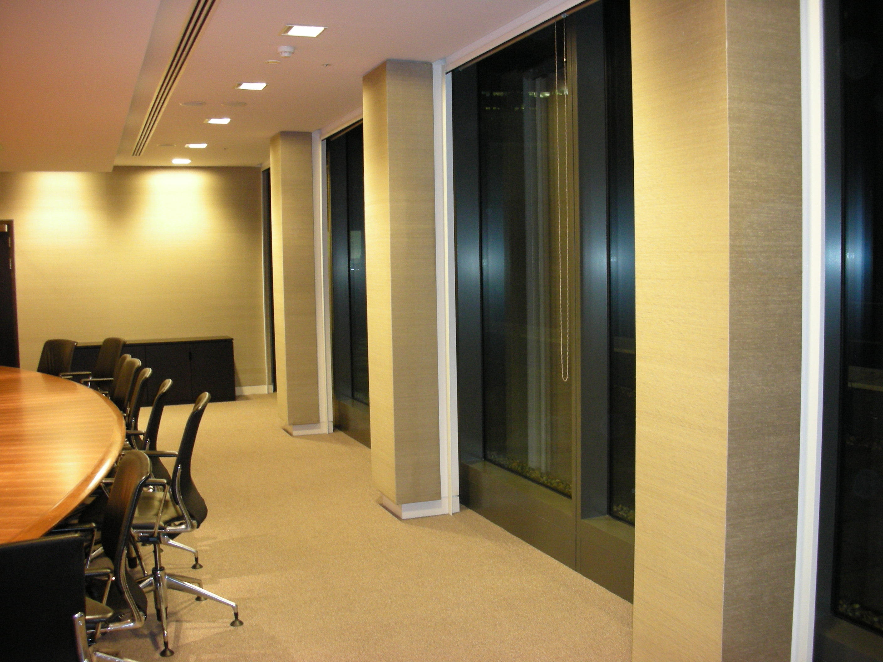 Modern conference room with a large wooden table and white chairs in a commercial office setting